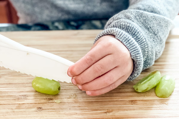 Preschooler cutting grapes