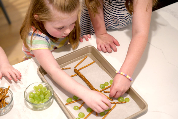 Children adding grapes to snack