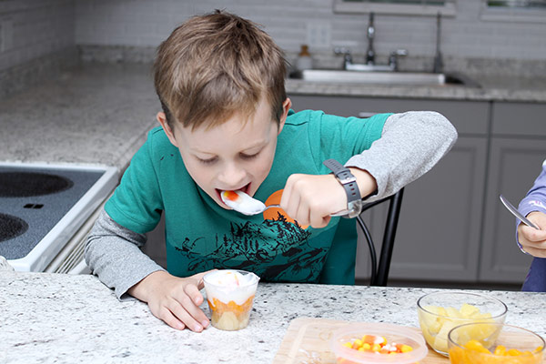 Child spooning pineapple chunks into a cup