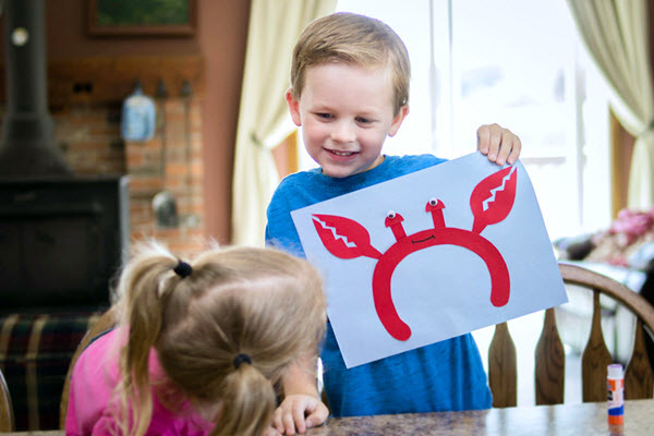 little boy holding up finished letter c craft