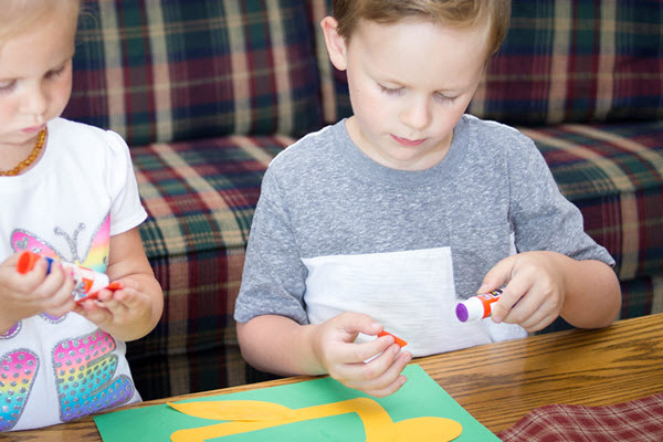boy gluing feet onto letter d craft