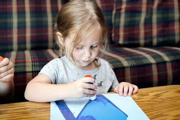 little girl gluing the body of her letter n craft