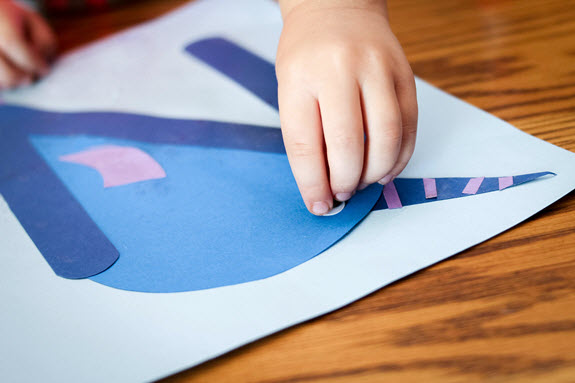 child gluing an eye on his letter n craft