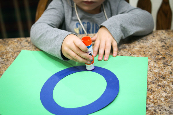 child putting glue on her letter o craft