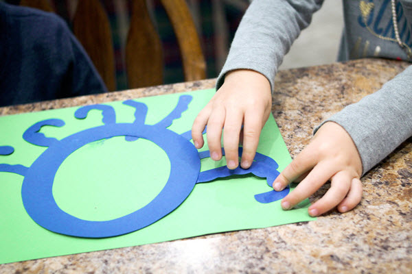 child gluing tentacles to her letter o craft