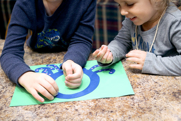 children attaching tiny dots to their letter o craft