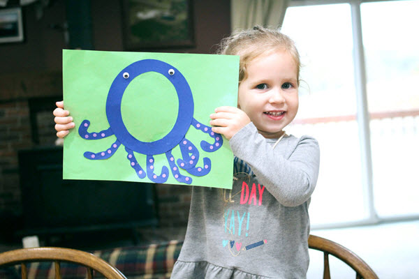 little girl showing off her completed letter o craft