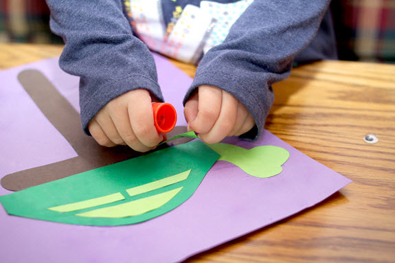 child gluing her letter T craft