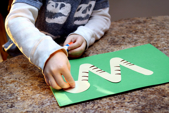boy gluing head on letter w craft