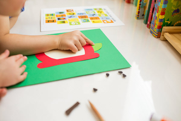 child putting a leaf on her lowercase a craft