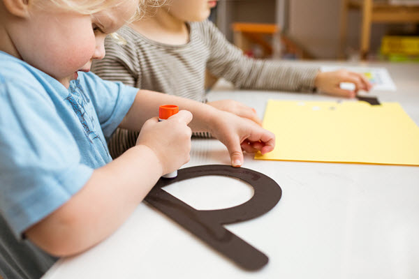 child glues her lowercase letter b craft
