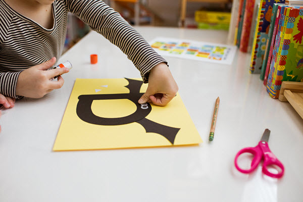 child attaching eyes to her letter b craft