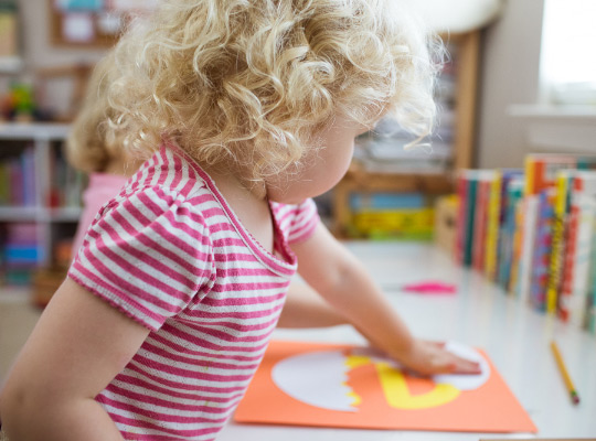 little girl creating lowercase e craft