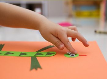 child applies googly eyes to lowercase i craft