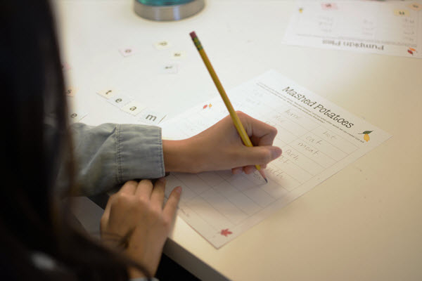 girl writes words on Thanksgiving Scramble words sheet