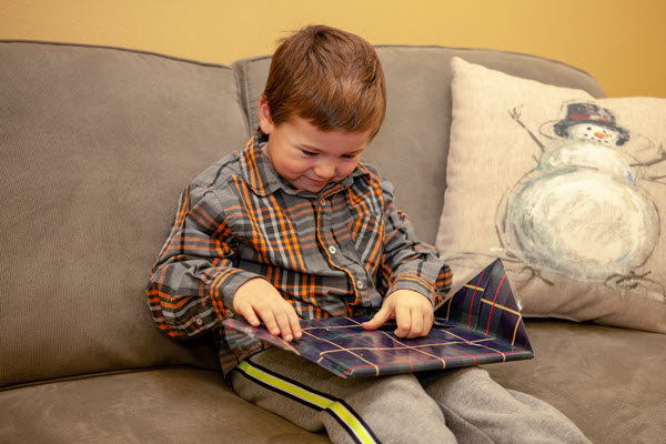 little boy unwraps picture book for book advent calendar