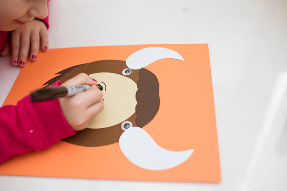 child draws a nose on her uppercase letter O craft