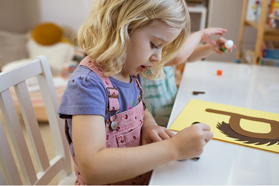 child applies glue to her uppercase letter P craft