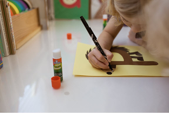 child draws a mouth on her uppercase letter P craft