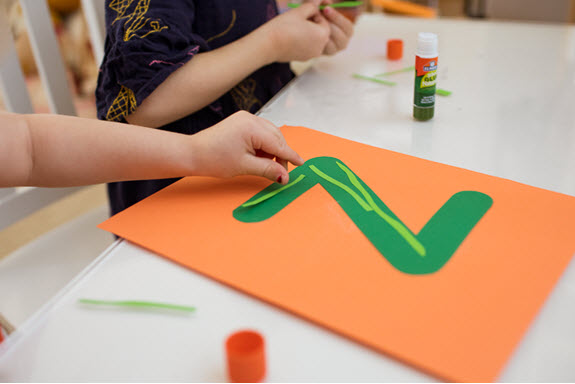 child adds piece to her lowercase z craft