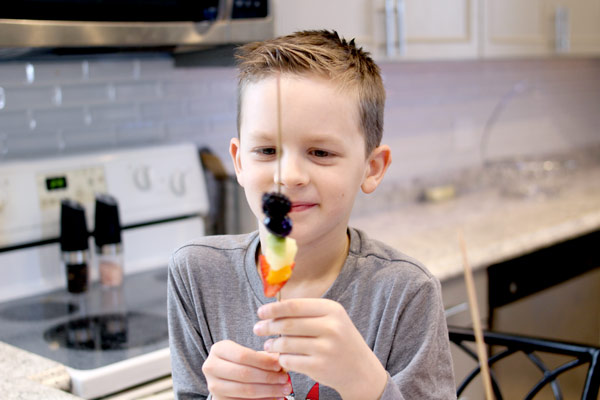 children eaiting rainbow fruit skewers